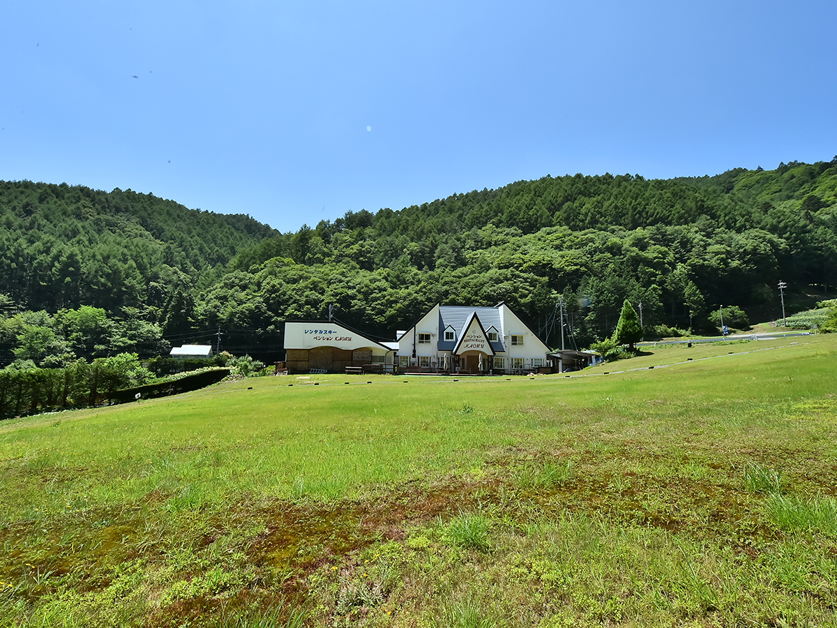 緑の芝生の向こうに建つペンションかおる